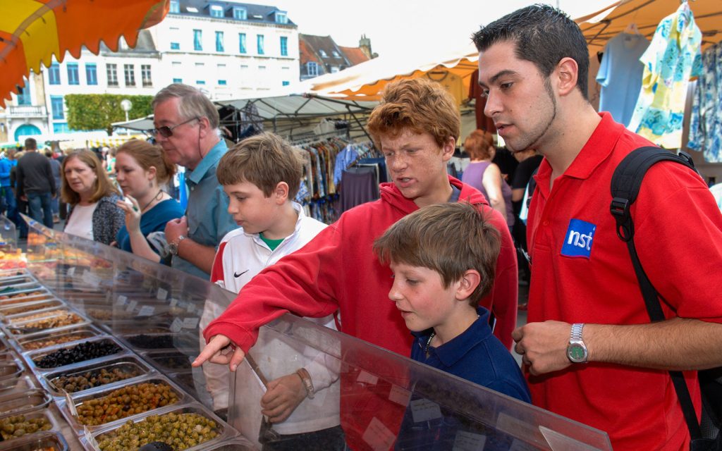 Tour Leader at a French marketplace with guests