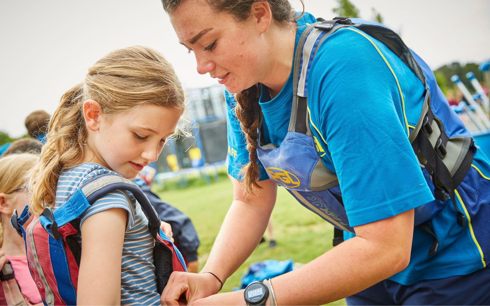 A PGL instructor putting a buoyancy aid on a child