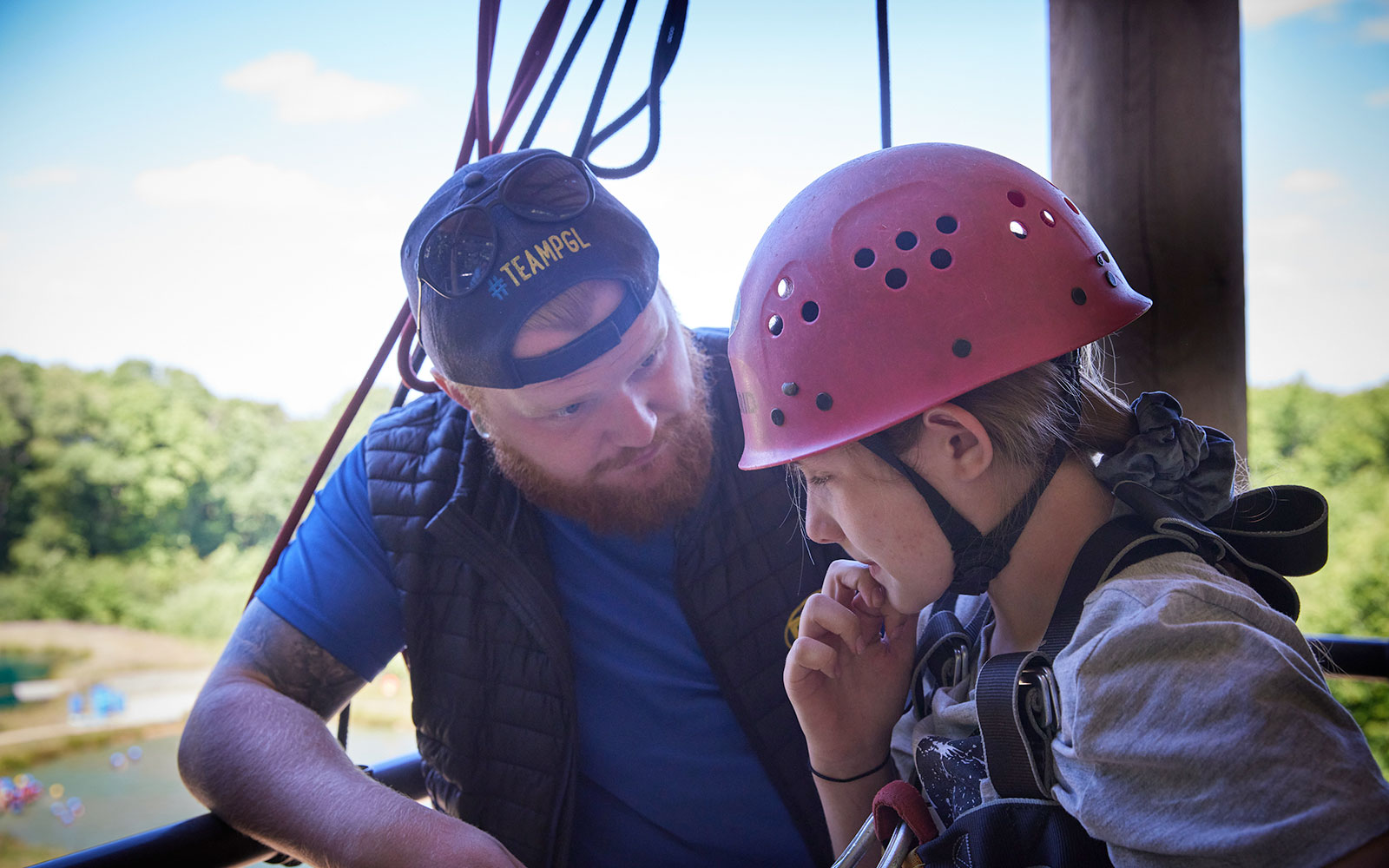 A PGL activity instructor helping a child on an abseil tower