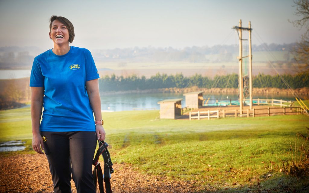 A PGL employee in the sunny grounds of Caythorpe Court with the lake and high ropes behind them.