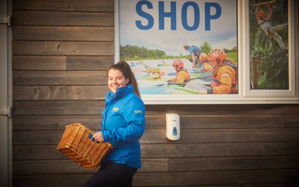 A PGL Retail Assistant carrying a hamper outside a shop